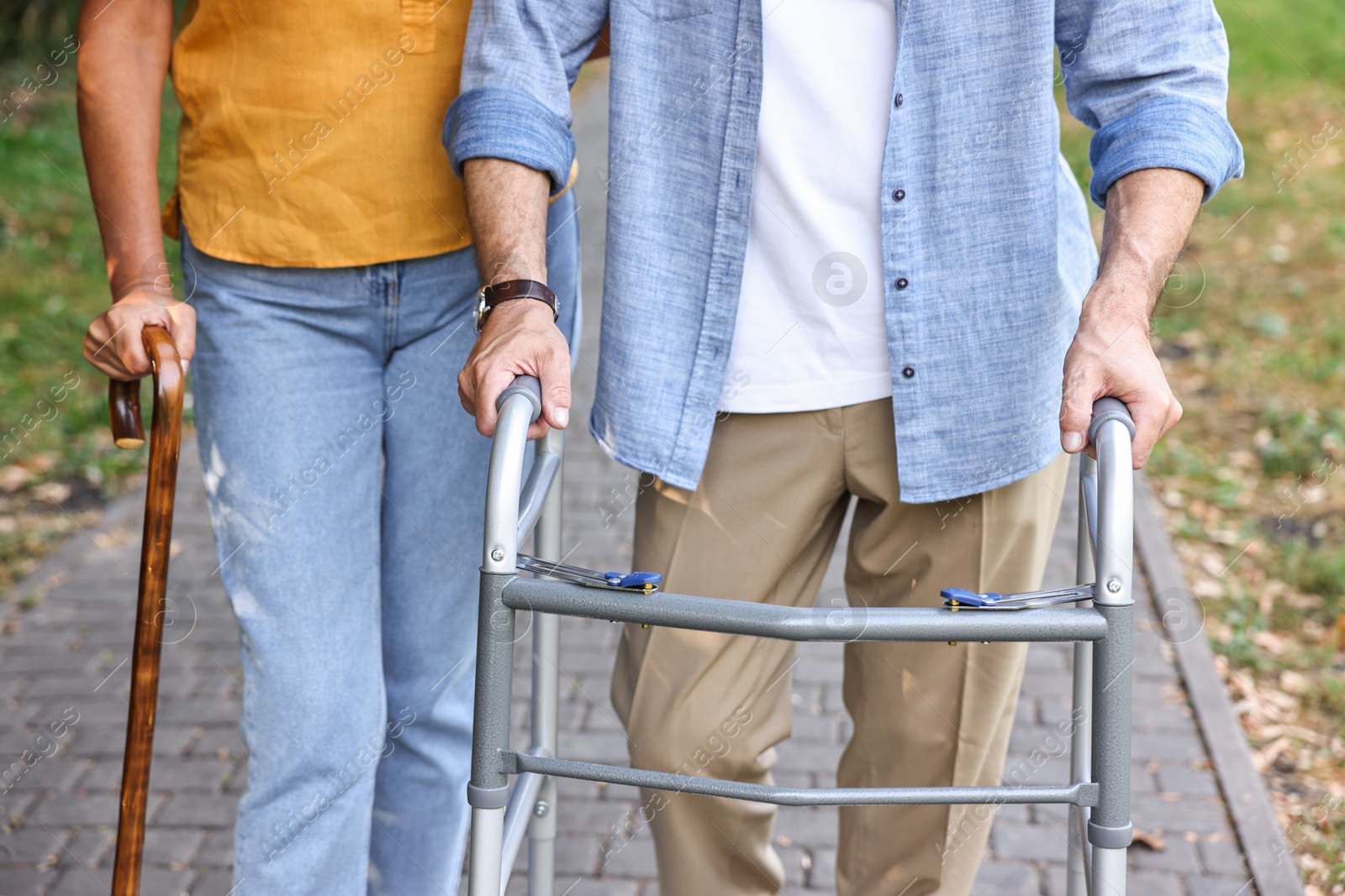 Photo of Senior couple with walking frame and cane in park, closeup