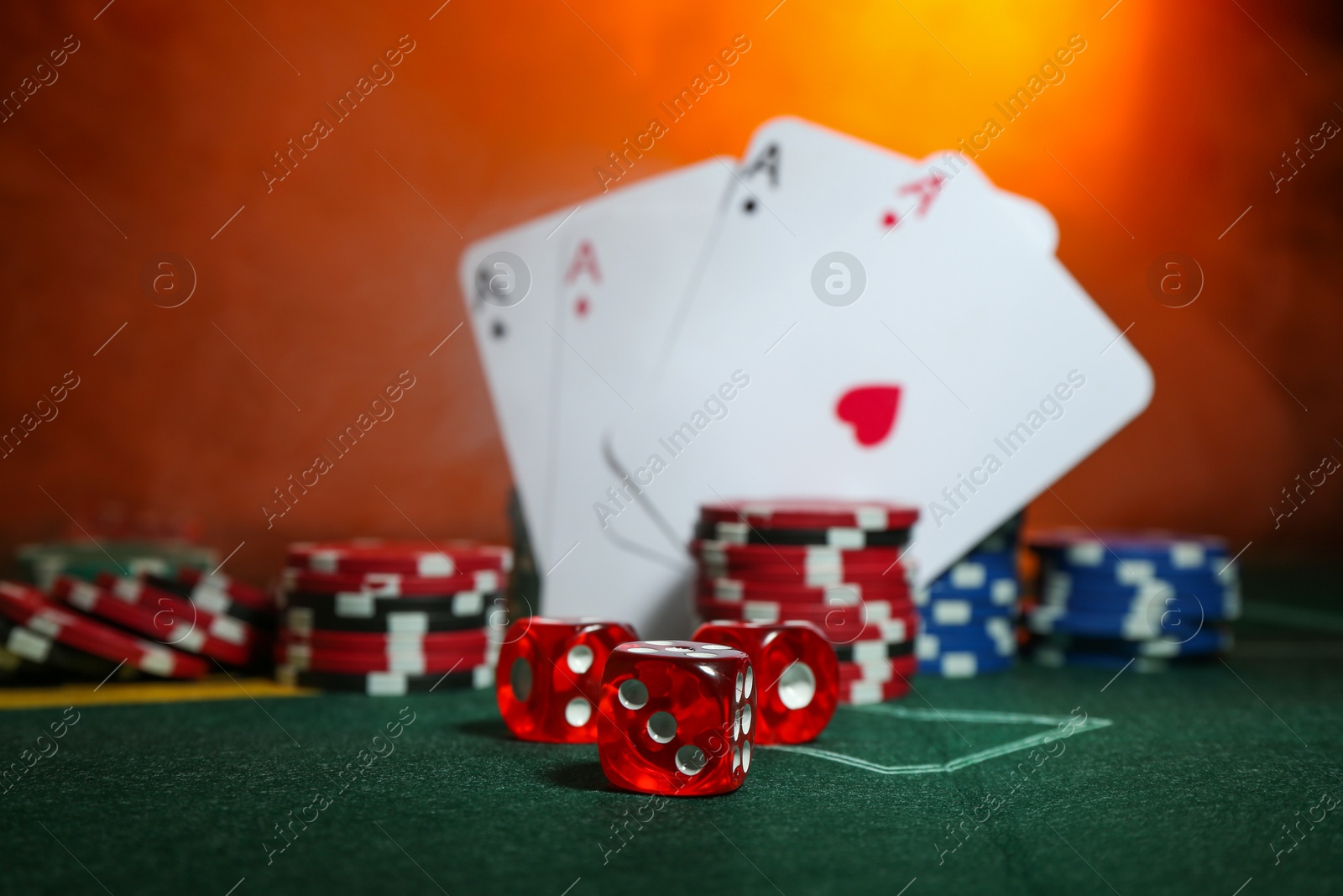 Photo of Dices, poker chips and playing cards on green table, selective focus