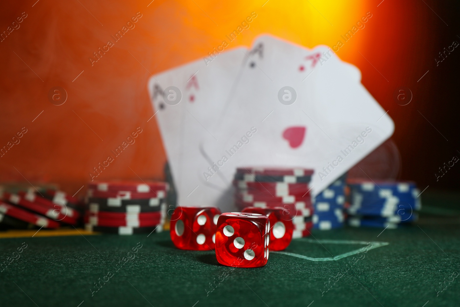 Photo of Dices, poker chips and playing cards on green table, selective focus