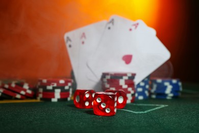 Dices, poker chips and playing cards on green table, selective focus