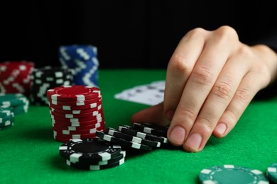 Photo of Woman with poker chips at green table, closeup