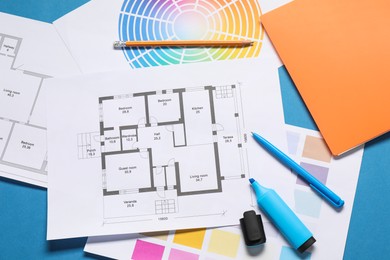 Photo of Designer's workplace with house plans, color palettes and stationery on blue table, flat lay