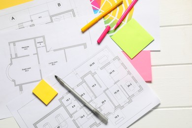 Photo of Designer's workplace with house plans, color palette and stationery on white wooden table, flat lay