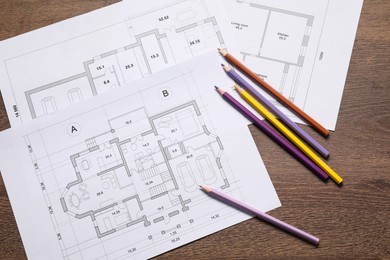 Photo of Designer's workplace with house plans and pencils on wooden table, flat lay