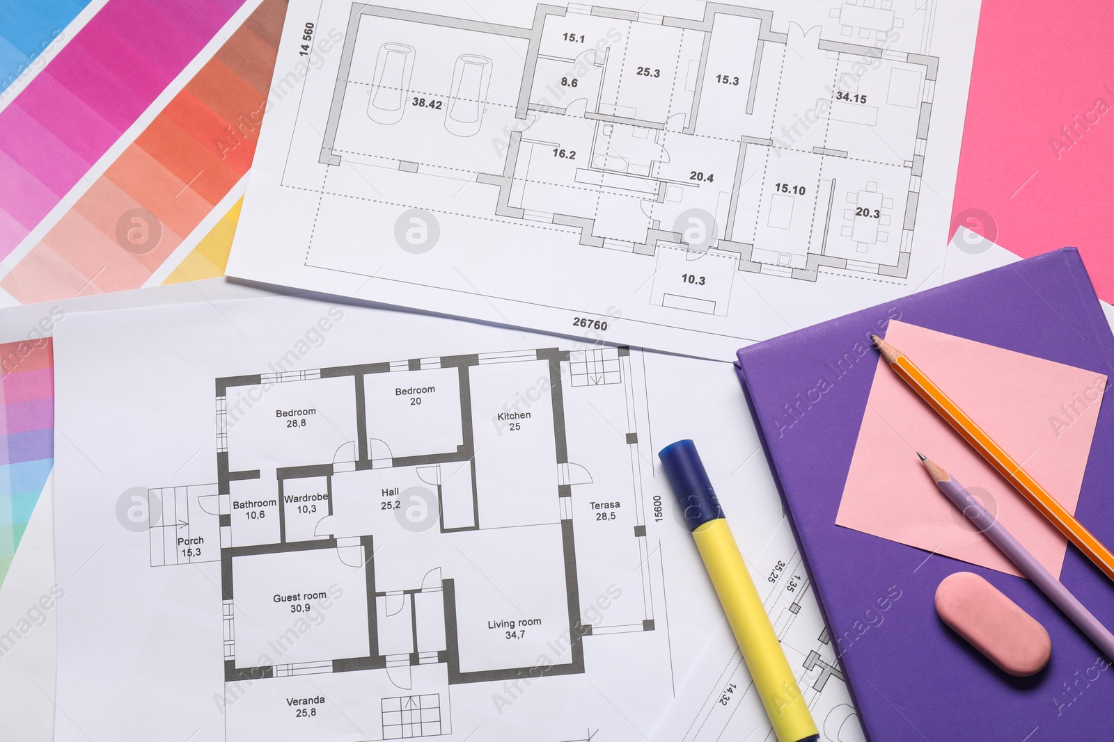 Photo of Designer's workplace with house plans, color palettes and stationery on table, top view