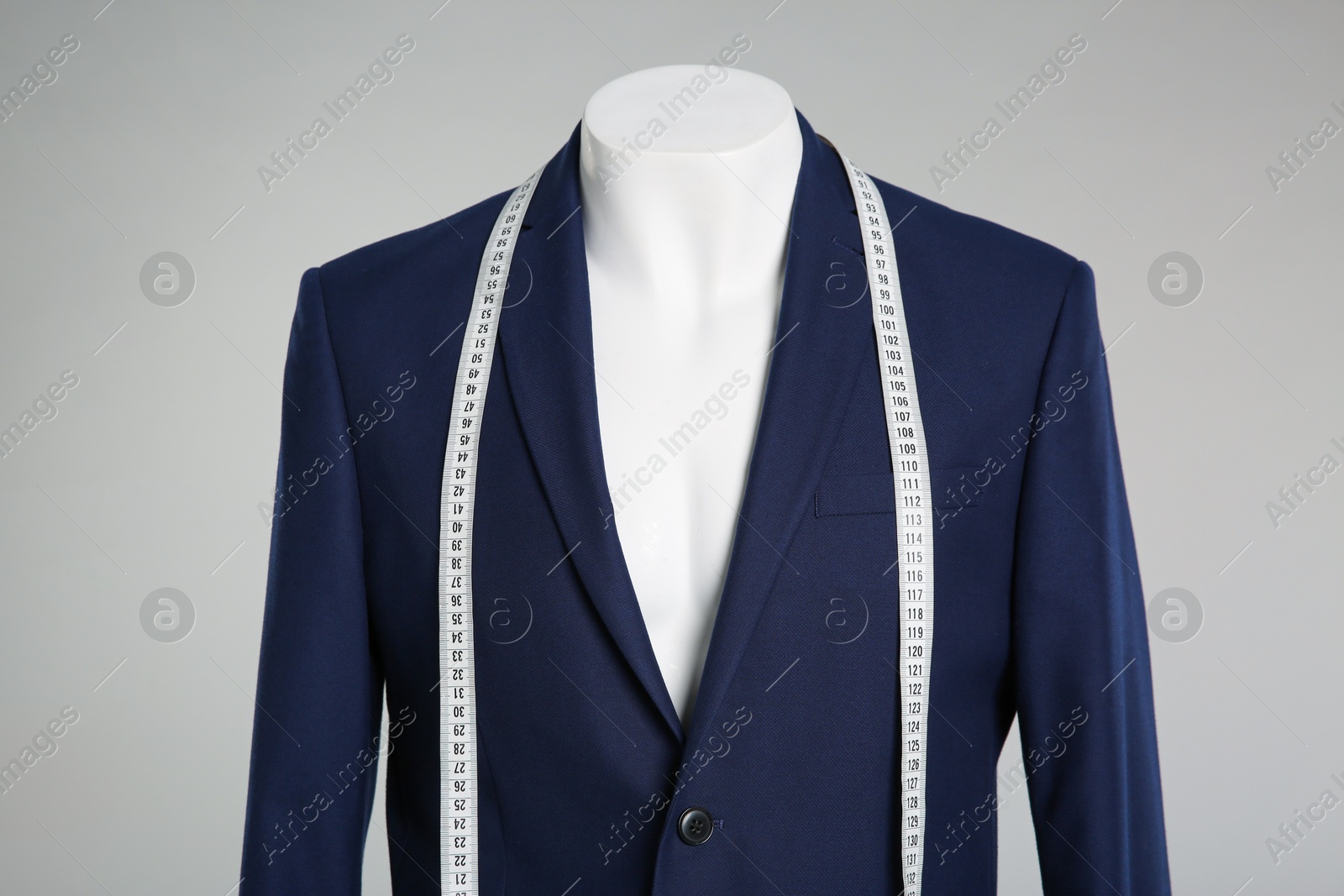 Photo of Male mannequin with elegant suit jacket and measuring tape on grey background