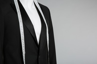 Male mannequin with elegant suit jacket and measuring tape on grey background. Space for text