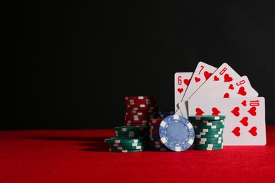 Photo of Poker chips and playing cards on red table, space for text