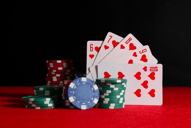 Poker chips and playing cards on red table