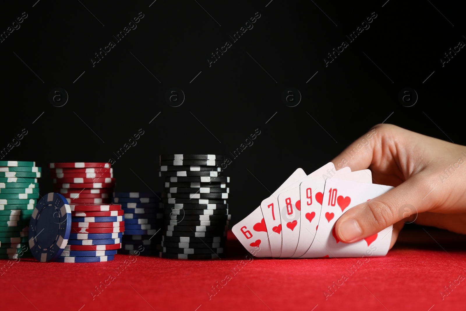 Photo of Woman with playing cards and poker chips at red table, closeup