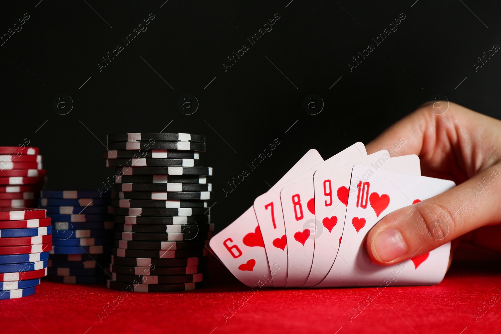 Photo of Woman with playing cards and poker chips at red table, closeup