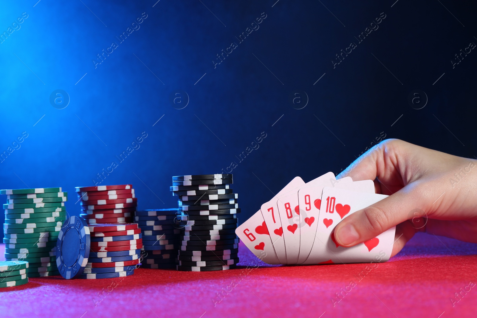 Photo of Woman with playing cards and poker chips at pink table, closeup