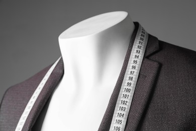 Photo of Male mannequin with brown jacket and measuring tape on grey background, closeup