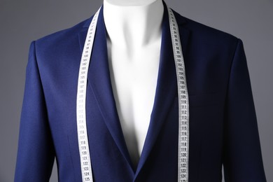 Photo of Male mannequin with blue jacket and measuring tape on grey background, closeup