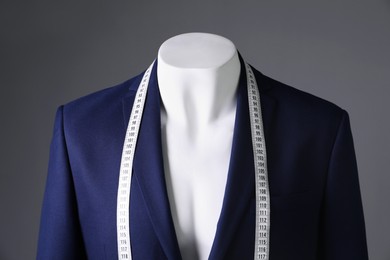 Photo of Male mannequin with blue jacket and measuring tape on grey background, closeup