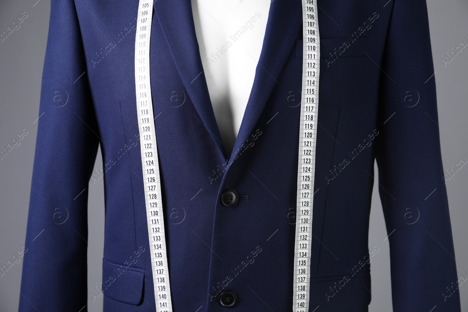 Photo of Male mannequin with blue jacket and measuring tape on grey background, closeup