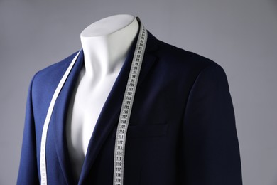 Male mannequin with blue jacket and measuring tape on grey background