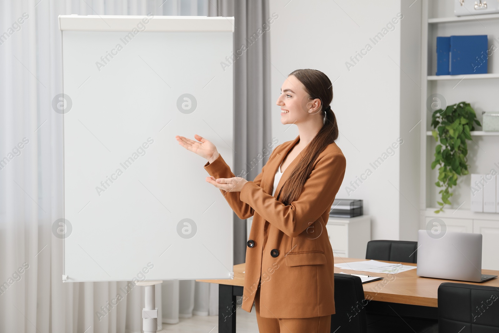 Photo of Happy woman near flip chart in office. Mockup for design