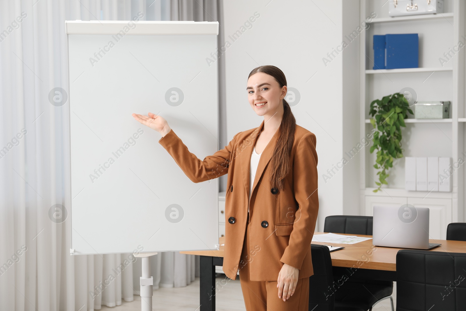 Photo of Happy woman near flip chart in office. Mockup for design