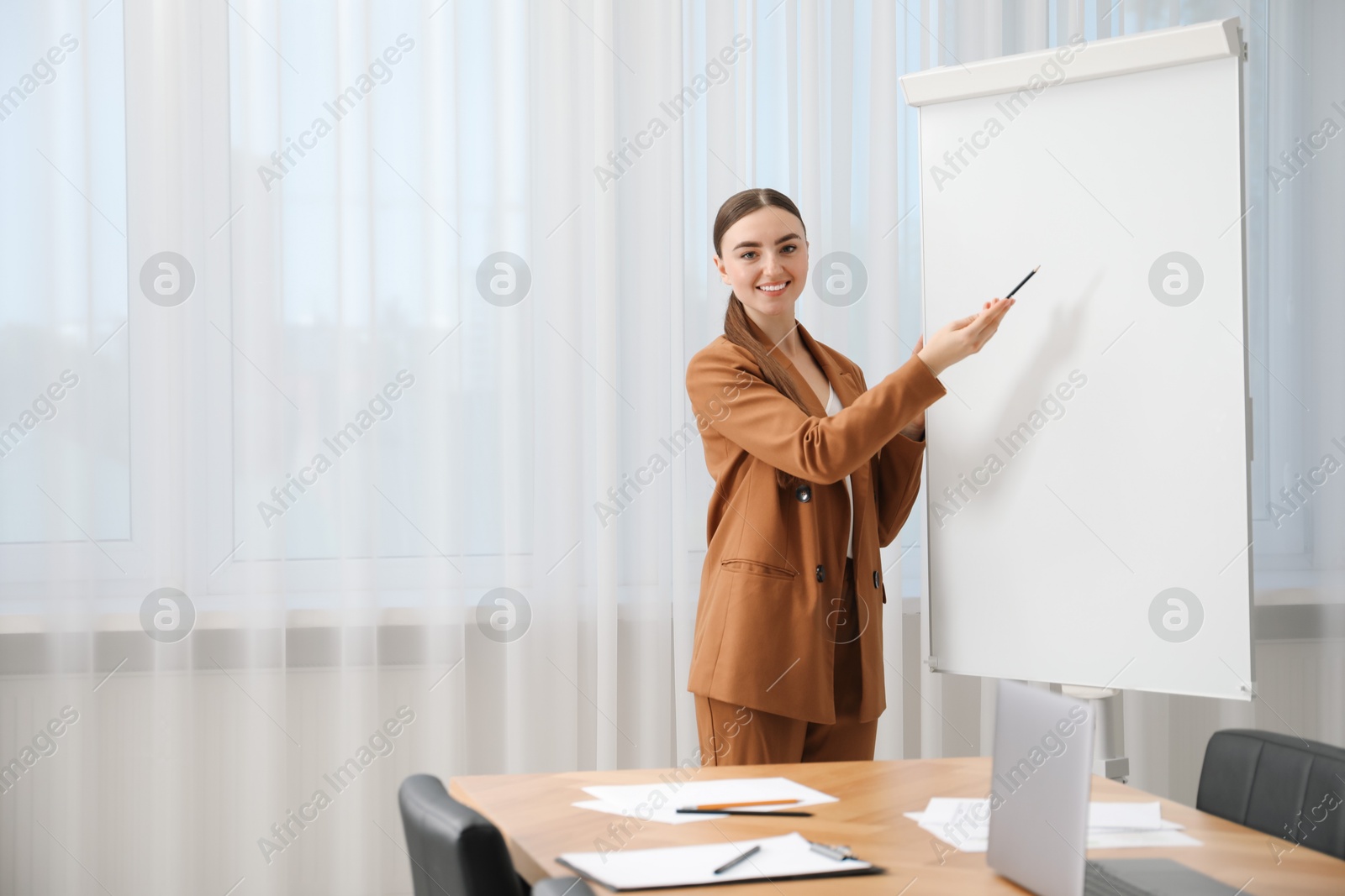 Photo of Happy woman near flip chart in office. Mockup for design