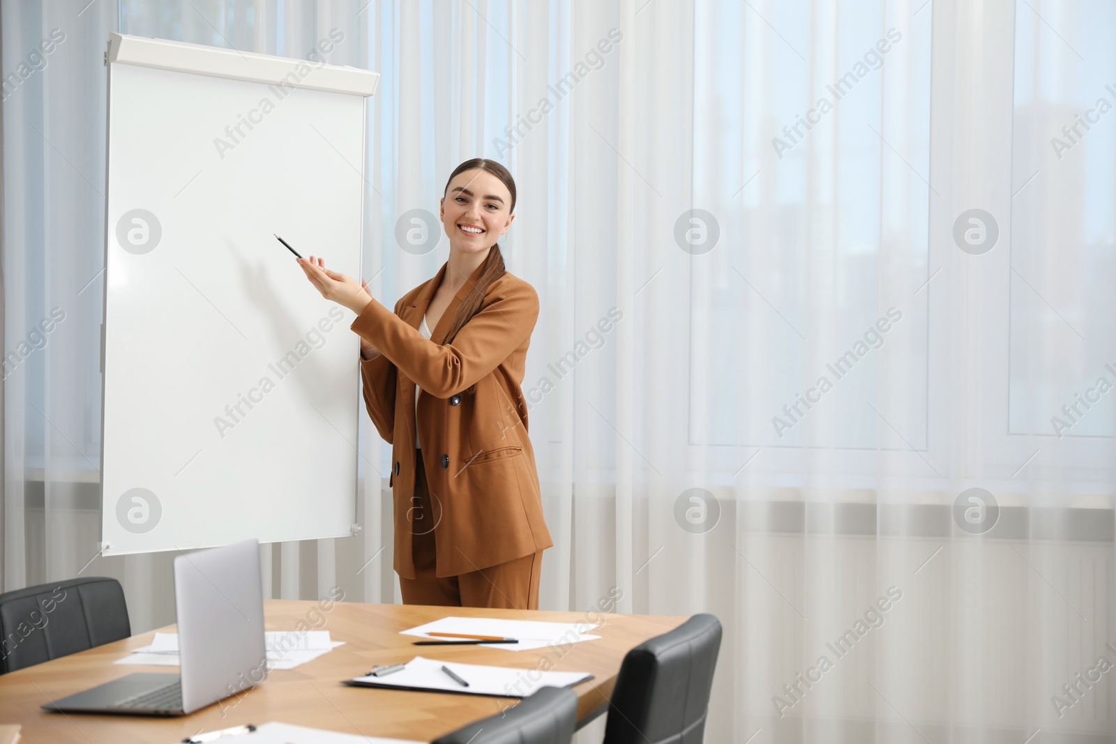 Photo of Happy woman near flip chart in office. Mockup for design