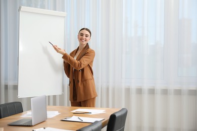 Photo of Happy woman near flip chart in office. Mockup for design