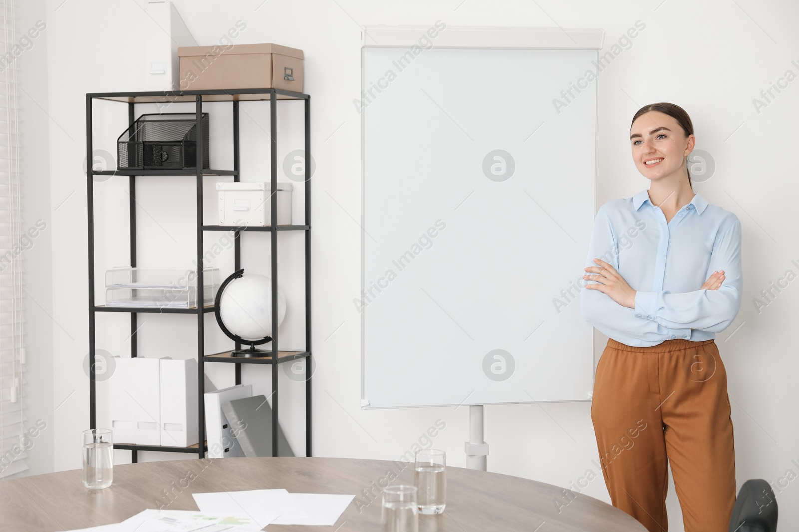 Photo of Happy woman near flip chart in office. Mockup for design