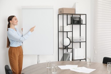 Photo of Happy woman near flip chart in office. Mockup for design