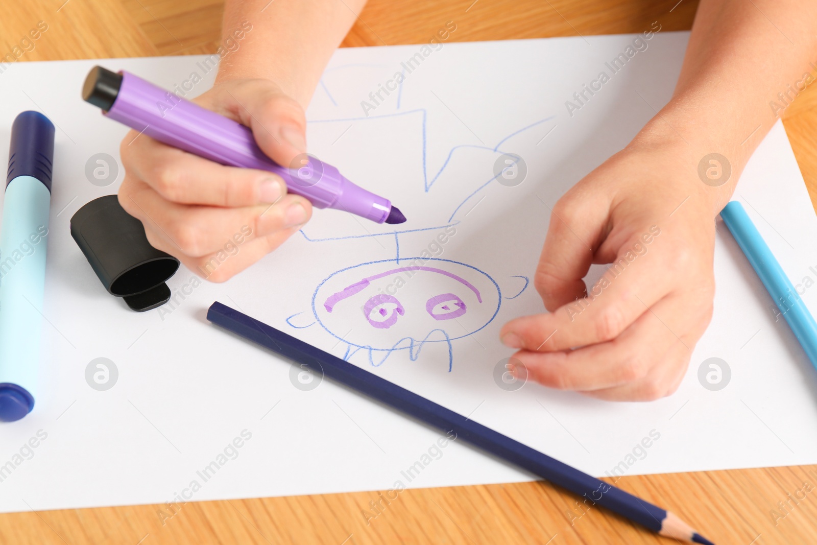 Photo of Boy drawing picture at wooden table, closeup