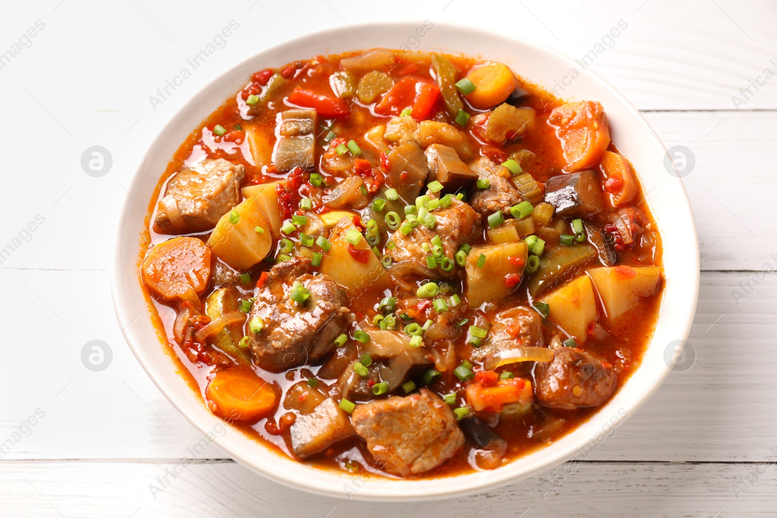 Photo of Delicious stew with vegetables in bowl on white wooden table, closeup