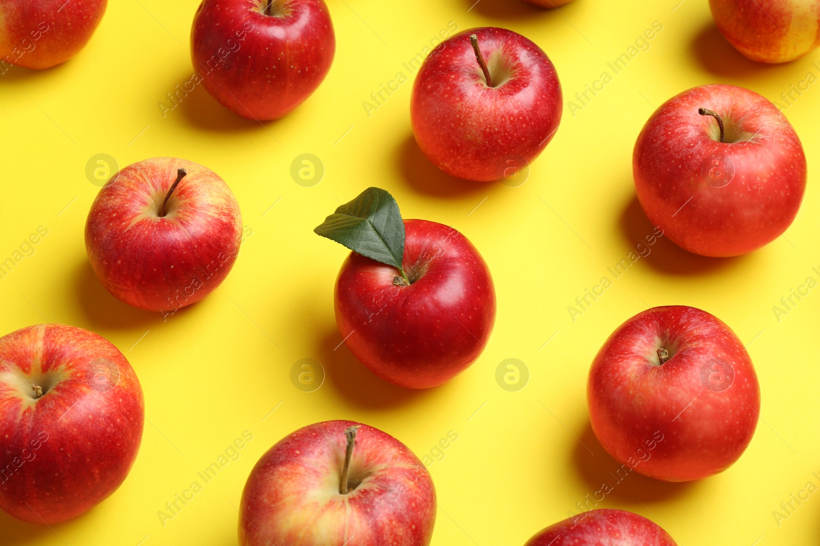 Photo of Many red apples on yellow background, above view