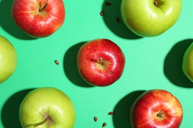 Flat lay composition with different apples and seeds on green background