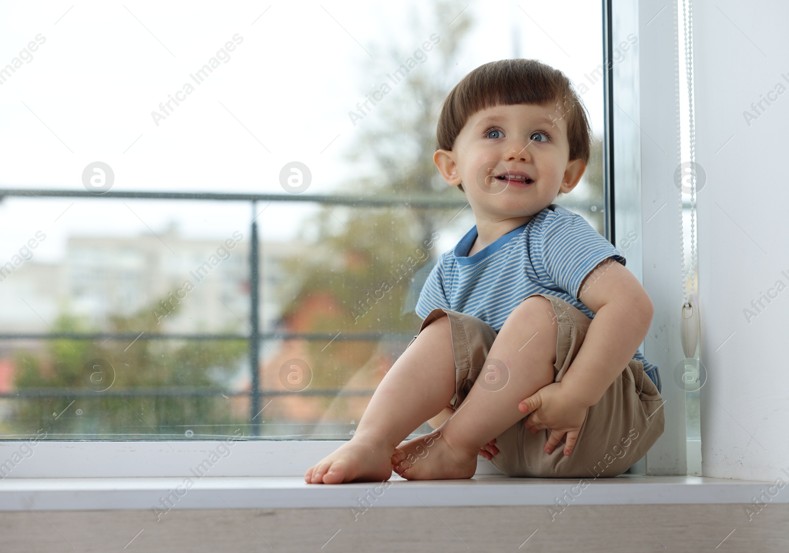 Photo of Little boy sitting on window sill, space for text. Child in danger