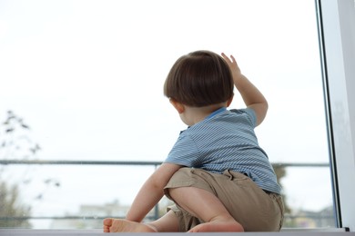 Photo of Little boy looking at window, back view with space for text. Child in danger