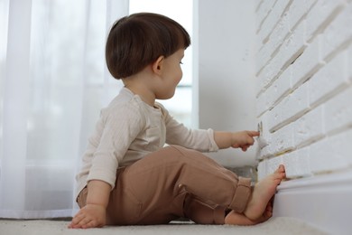 Photo of Little boy playing with electrical socket at home. Child in danger