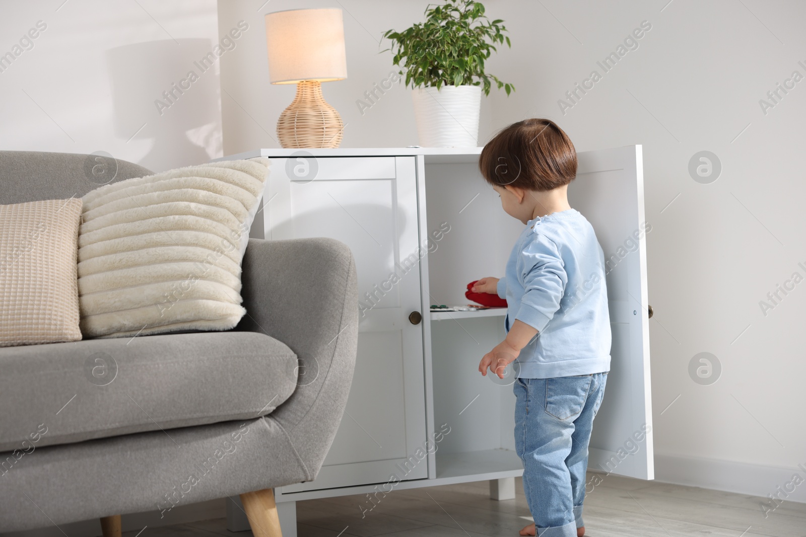 Photo of Little boy finding cabinet with pills at home. Child in danger