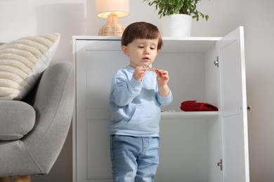 Photo of Little boy with pills near cabinet at home. Child in danger