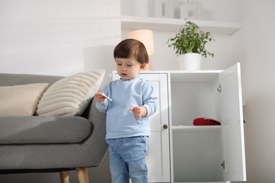 Photo of Little boy with pills near cabinet at home. Child in danger