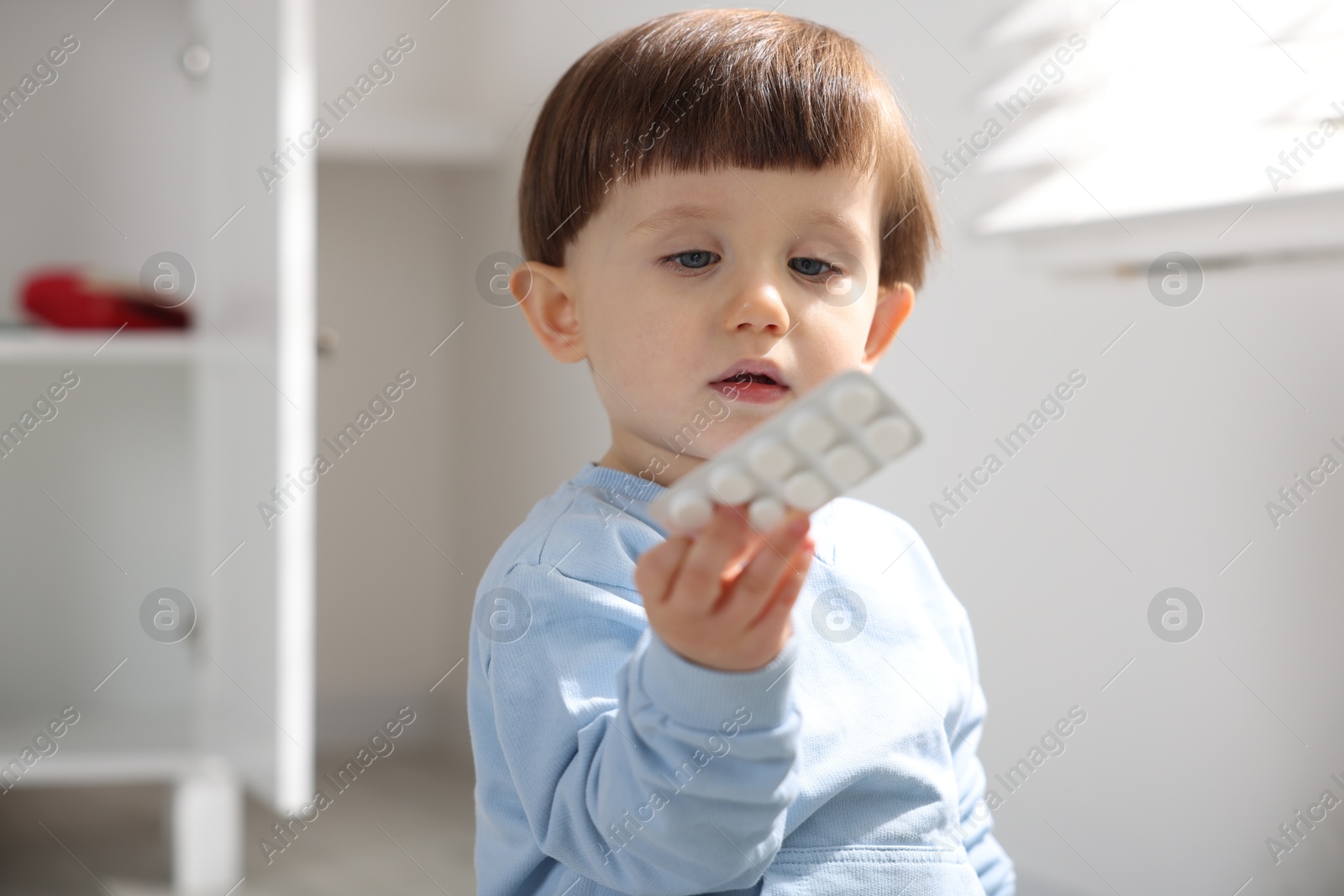 Photo of Little boy with pills at home. Child in danger