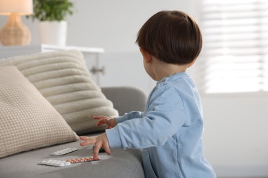 Photo of Little boy playing with pills at home. Child in danger