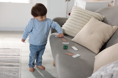 Photo of Little boy playing with pills at home. Child in danger