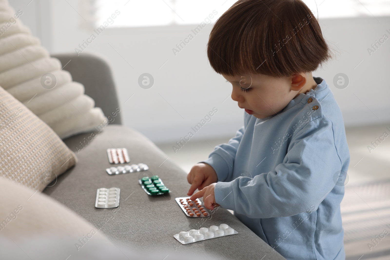 Photo of Little boy playing with pills at home. Child in danger