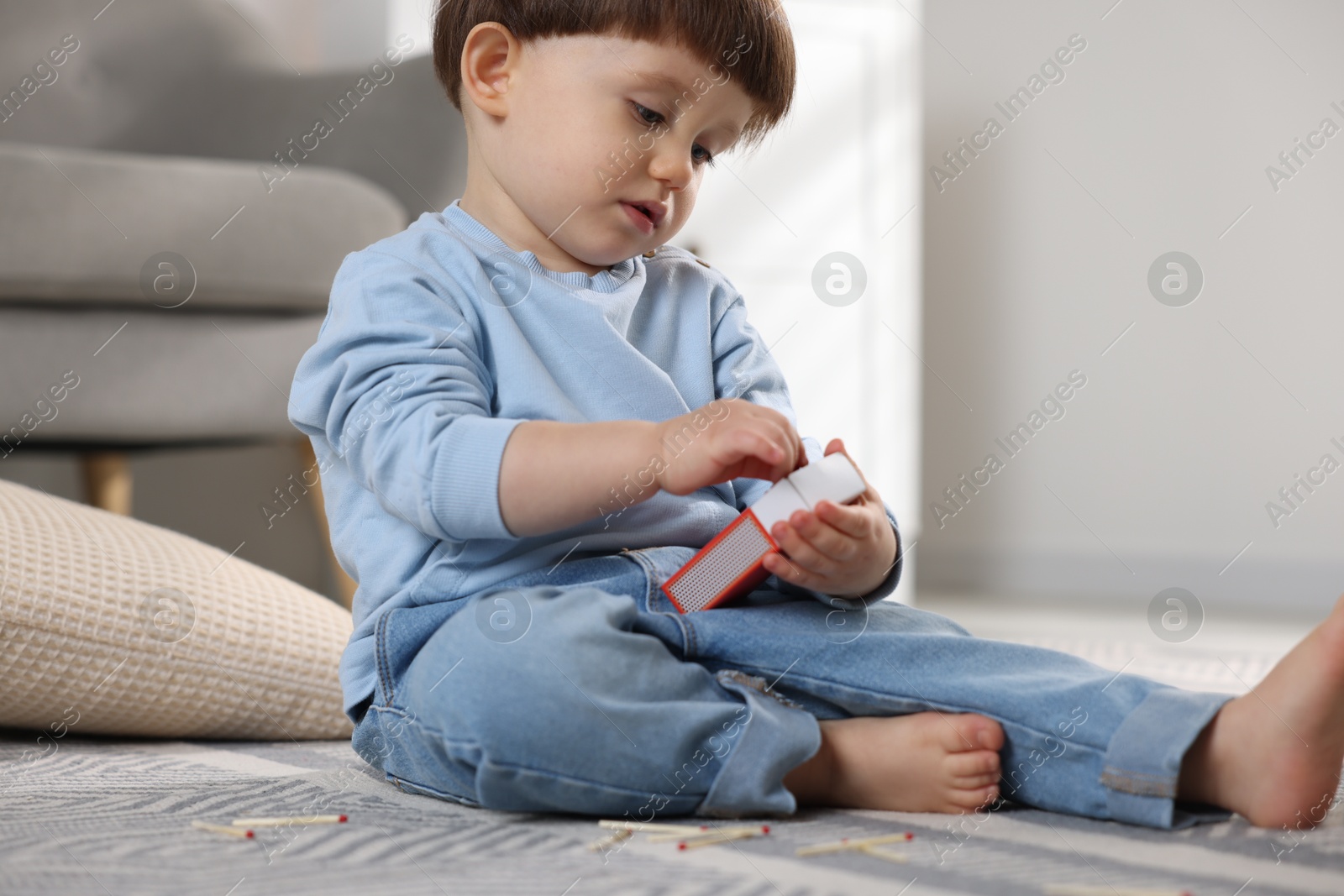 Photo of Little boy playing with matchbox at home. Child in danger