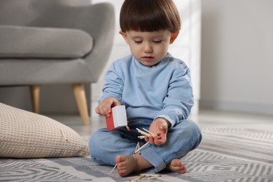 Photo of Little boy playing with matches at home. Child in danger