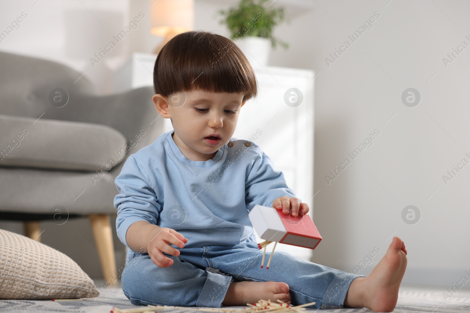 Photo of Little boy playing with matchbox at home. Child in danger