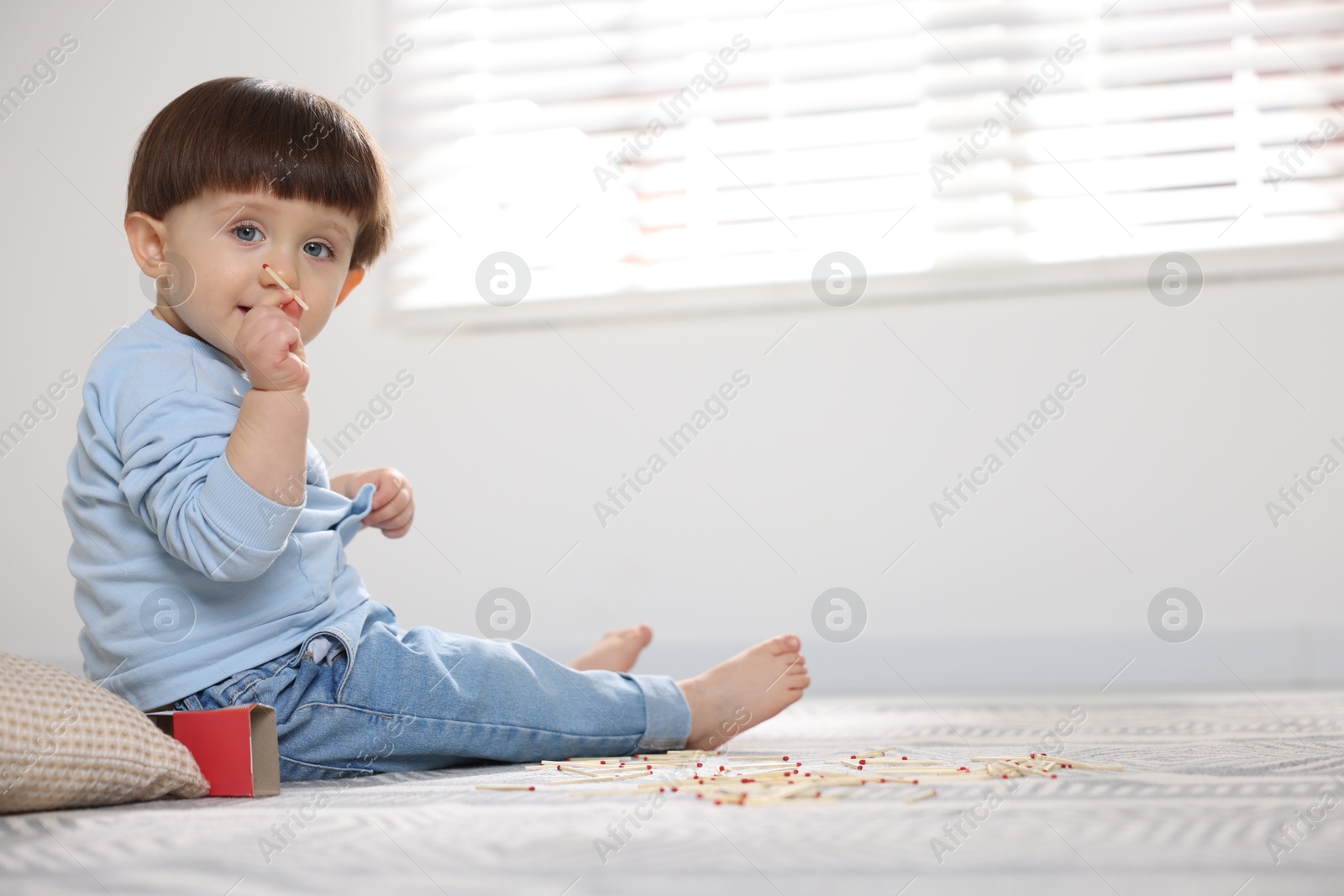 Photo of Little boy playing with matches at home, space for text. Child in danger