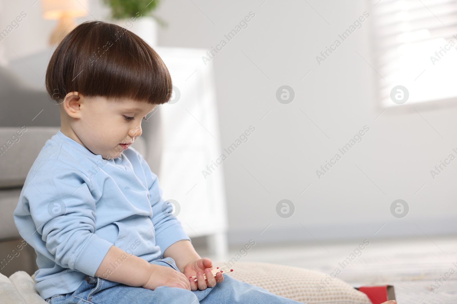 Photo of Little boy playing with matches at home, space for text. Child in danger