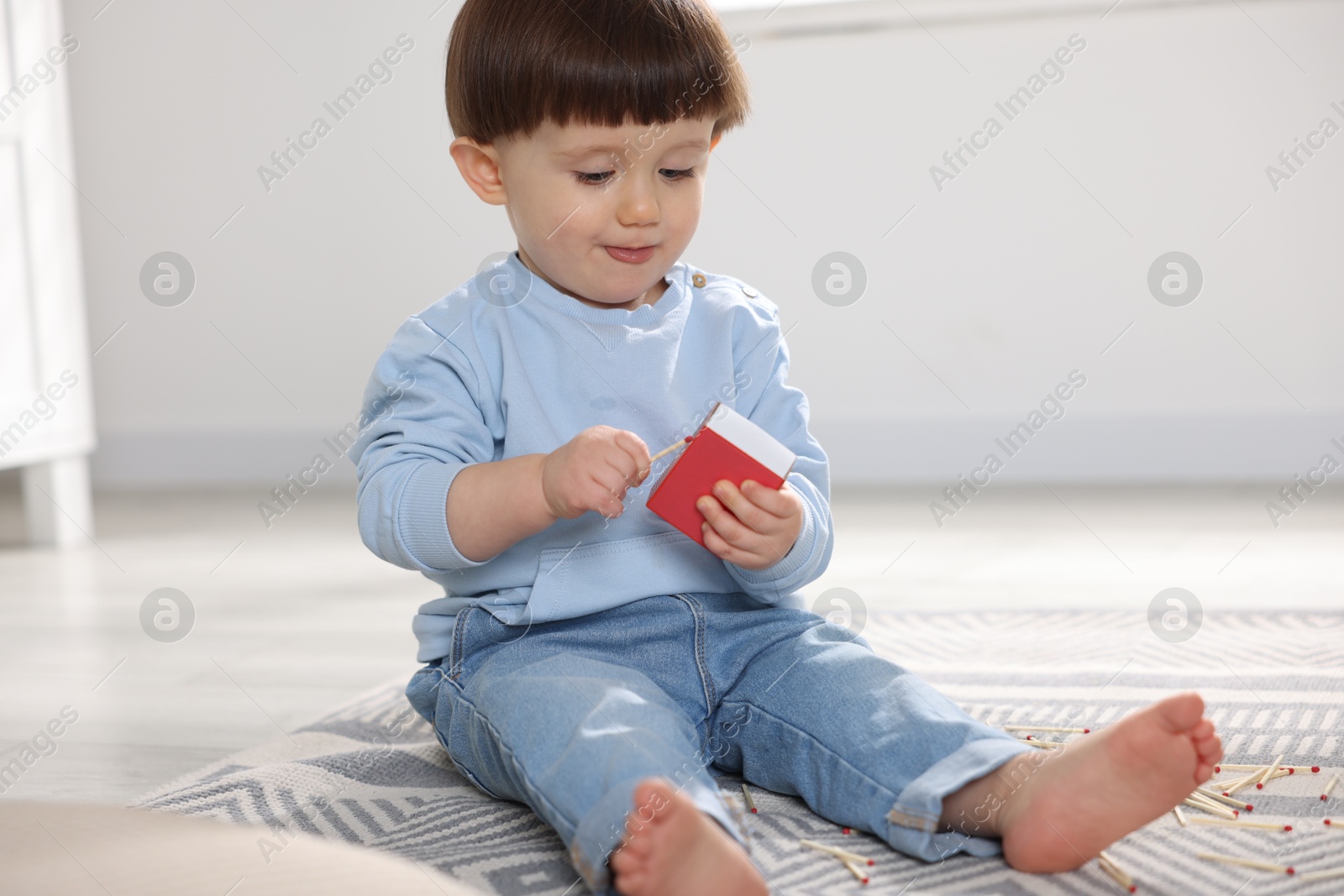 Photo of Little boy playing with matchbox at home. Child in danger