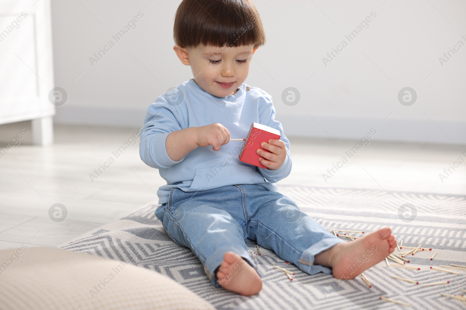 Photo of Little boy playing with matchbox at home. Child in danger