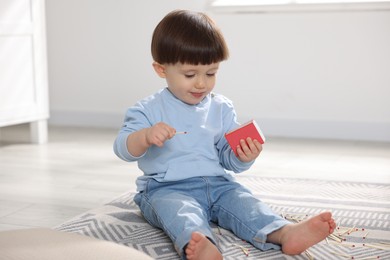 Photo of Little boy playing with matchbox at home. Child in danger